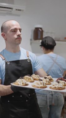 Baker mutfakta bir tepsi taze kruvasan gösteriyor.
