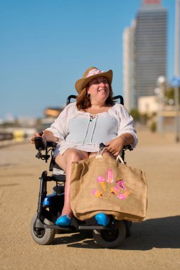 Barcelona, İspanya 'da yaz tatilinin tadını çıkaran tekerlekli sandalyeyle gülümseyen kadın.