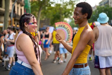 Genç çift el ele tutuşup gökkuşağı hayranımızı gösteriyor. Gurur festivalinde aşkı ve çeşitliliği kutluyorlar.