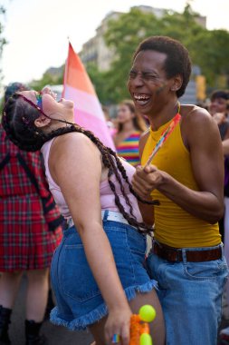İki arkadaş bir gurur festivalinde gülüyor ve eğleniyorlar, çeşitlilik ve kapsamı kutluyorlar.
