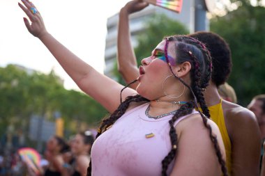 Genç bir kadın bir gurur festivalinde kutlama yapıyor, canlı gökkuşağı makyajıyla neşe içinde dans ediyor, aşkı, çeşitliliği ve özgürlüğü somutlaştırıyor.