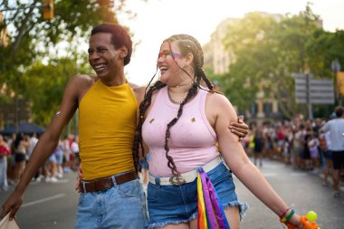 Gurur geçidinde yürürken kucaklaşan ve gülen iki insan, lgbtq haklarına olan sevgilerini ve desteklerini gösteriyorlar.