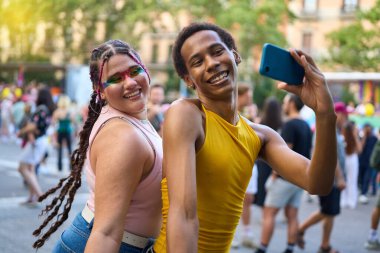 Gurur festivalinde iki arkadaş bir akıllı telefonla selfie çekiyor, çeşitliliği ve lgbtq haklarını kutluyorlar.