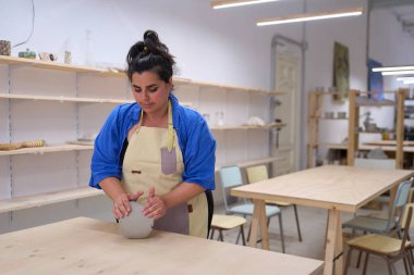 Dişi zanaatkar, rahat seramik atölyesinde ham kili ustalıkla şekillendirip güzel bir çömlek haline getiriyor, yaratıcılık ve zanaatkarlık sergiliyor.