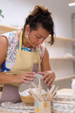 Seramik atölyesindeki bir kalıpta kadın esnaf kil şekillendiriyor. Küçük işletme sahibi yeni bir çömlek yapımında çalışıyor.