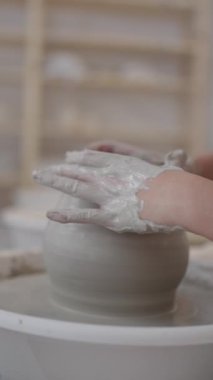 Yetenekli çömlekçi çanak çömlek çarkı üzerinde dikkatlice şekil veriyor, yumuşak kilden geleneksel atölye ortamındaki zarif seramik vazoya dönüştürüyor.