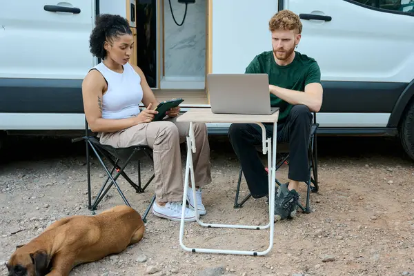 İki serbest çalışan dizüstü bilgisayarları ve tabletleri üzerinde çalışıyor, köpekleriyle karavanda seyahat ederken uzaktan çalışma özgürlüğünün tadını çıkarıyorlar.