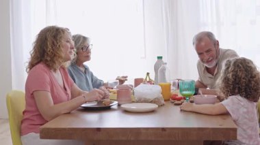 Mutfak masasında çok nesilli aile toplantısı, sabah yemeğini sıcak bir etkileşim ve büyük anne ve çocuk arasındaki sevgi dolu bir bağ ile paylaşıyoruz.