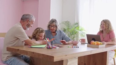 Annesi video konferansına katılırken büyükannesi ve büyükbabası torunlarına ev ödevlerinde yardım ediyorlar. Yavaş çekim