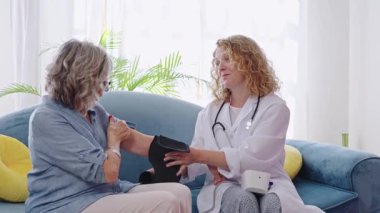 Evde sağlık kontrolü sırasında yaşlı bir kadının tansiyonunu ölçmek, kişiselleştirilmiş yaşlılık bakımı ve sağlık kontrolü sağlamak,