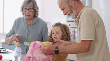 Sevgi dolu büyükbabalar torunlarına okul için pembe sırt çantasını hazırlamalarında yardım ederler. Başarılı bir gün için ihtiyacı olan her şeye sahip olmasını sağlarlar.