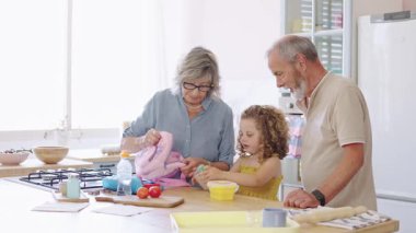 Büyükbabalar torunlarına okul yemeği hazırlar. Sırt çantasını parlak bir mutfağa koyar.