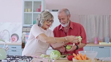 Üst düzey bir çift mutfakta sebze soyuyor ve kesiyor, sağlıklı bir yaşam tarzının tadını çıkarıyorlar.