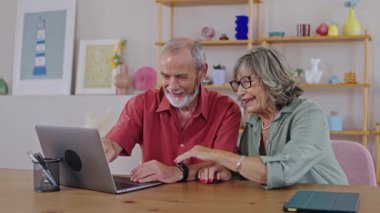 Olgun çift birlikte içeriği izlerken kahkahalarını paylaşıyor, rahat ev ortamında rahatlama anında teknolojiyle meşgul oluyorlar.