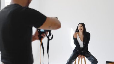 Yavaş çekim modada manken pozu ve fotoğrafçı beyaz stüdyoda fotoğraf çekiyor.