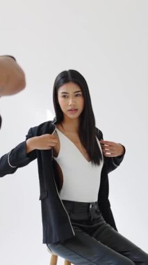 Stüdyoda fotoğrafçıya poz veren profesyonel model yavaş çekimde çeşitli kıyafet ve stilleri sergiliyor.