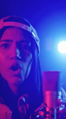 Yetenekli genç bayan şarkıcı şarkısını sahnede tutkuyla söylüyor, canlı mavi ve kırmızı ışıklar, yavaş çekim