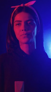 Kayıt stüdyosunda mikrofonla şarkı söyleyen genç bir kadının neon ışıklarla aydınlatıldığı yavaş çekim videosu.