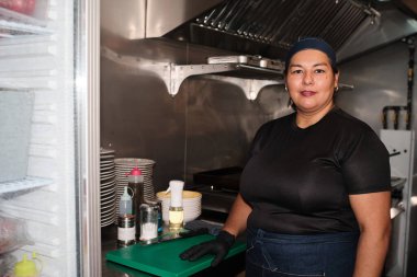 Woman chef standing in a commercial kitchen, wearing uniform and looking at the camera, showing professionalism in restaurant
