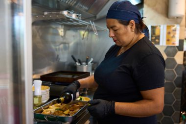 Professional chef preparing a savory meal with poultry and potatoes in a commercial kitchen, pouring wine into baking pan