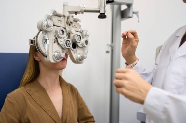 Patient receiving an eye exam and vision test by optometrist, assessing eyesight and refractive error in ophthalmology clinic
