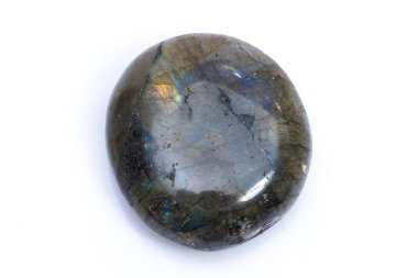 Beyaz arka planda doğal değerli taş labradorit izole edilmiş. Koyu gri labradoritin arka planında yanardöner bir parıltı var.