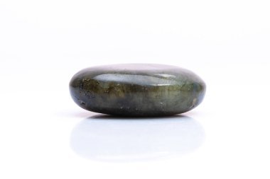 Beyaz arka planda doğal değerli taş labradorit izole edilmiş. Koyu gri labradoritin arka planında yanardöner bir parıltı var.