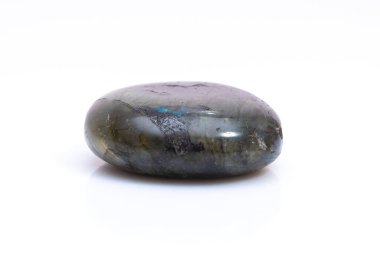 Beyaz arka planda doğal değerli taş labradorit izole edilmiş. Koyu gri labradoritin arka planında yanardöner bir parıltı var.