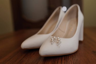 Beyaz kadın deri ayakkabılarında inci küpeler. Gelinin aksesuarları, gelinin sabahı.