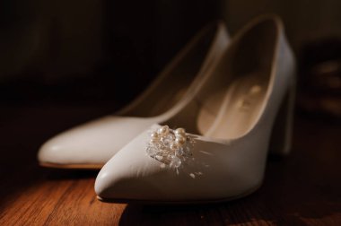 Beyaz kadın deri ayakkabılarında inci küpeler. Gelinin aksesuarları, gelinin sabahı.