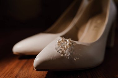 Beyaz kadın deri ayakkabılarında inci küpeler. Gelinin aksesuarları, gelinin sabahı.