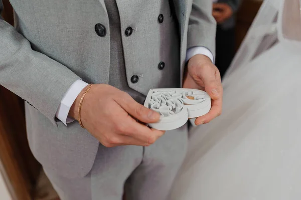 男の手にハートの形をした白い木製の箱の中に金の結婚指輪のペア — ストック写真