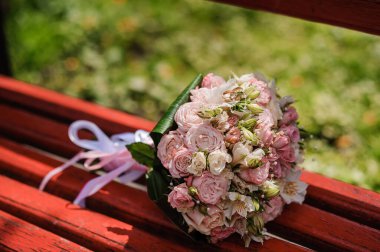 Gelinin buketinde renkli çiçeklerle bir çift altın alyans..