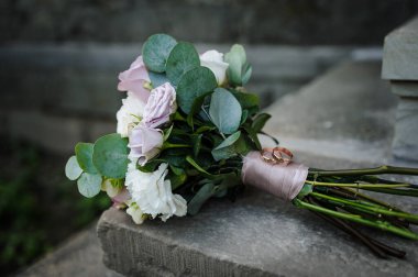 Gelinin buketinde renkli çiçeklerle bir çift altın alyans..