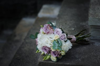 Gelinin buketinde renkli çiçeklerle bir çift altın alyans..