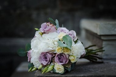 Gelinin buketinde renkli çiçeklerle bir çift altın alyans..