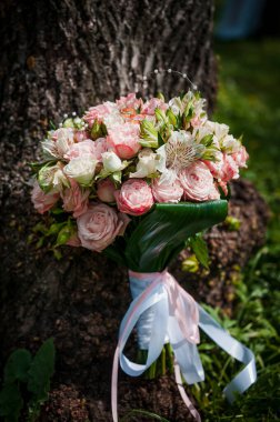 Gelinin buketinde renkli çiçeklerle bir çift altın alyans..