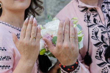 Yeni evlilerin elinde evlilik yüzükleri var. Bir erkek ve bir kızın ellerinde altın yüzükler.