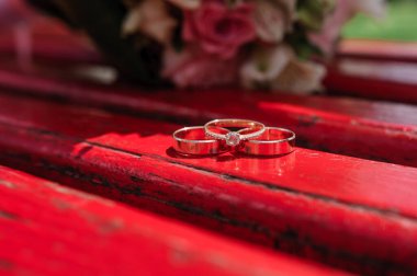 Altın alyanslar, arka planda gelin çiçekleri..