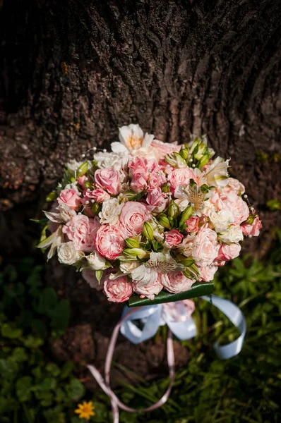 Wedding bouquet of the bride with flowers, tree in the background. Bridal bouquet with white and pink flowers.