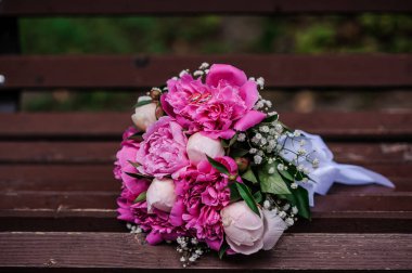 Pembe şakayık demetinde bir çift altın alyans.