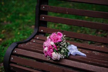 Pembe şakayık demetinde bir çift altın alyans.