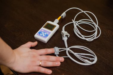 Man using pulse oximeter measures oxygen saturation level, health care monitoring concept. Pulse oximeter on brown background.