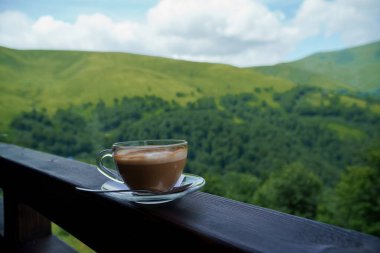 A mug of coffee with milk on a background of mountains