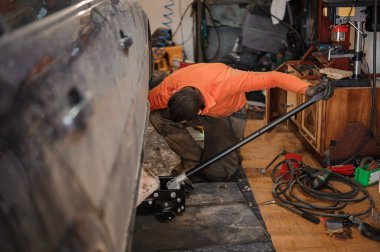 Tamirci arabanın şasisini tamir ediyor. Bir adam garajda bir araba tamir eder. Araba tekerleği tamiri