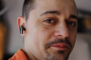 Otomobil tamircisi arabanın önünde garajın yanında duruyor. Garajın yanında kirli elbiseli bir adam duruyor.