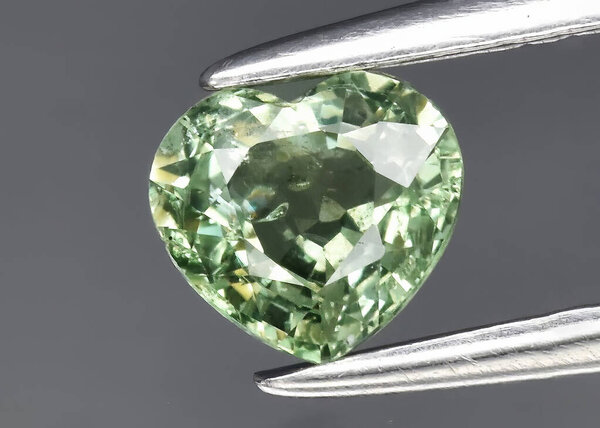Natural gem green sapphire on gray background