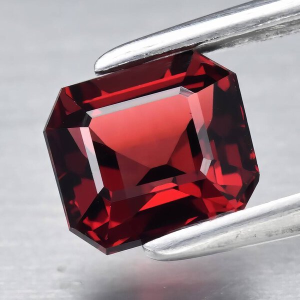 Natural gem red rhodolite garnet on gray background