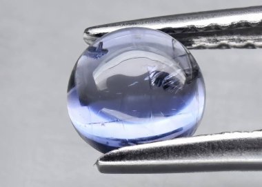 Gri arkaplanda doğal değerli taş mavisi iyolit.