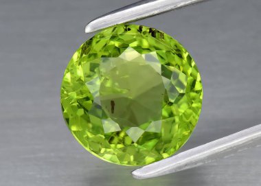 Natural gem green peridot on gray background clipart